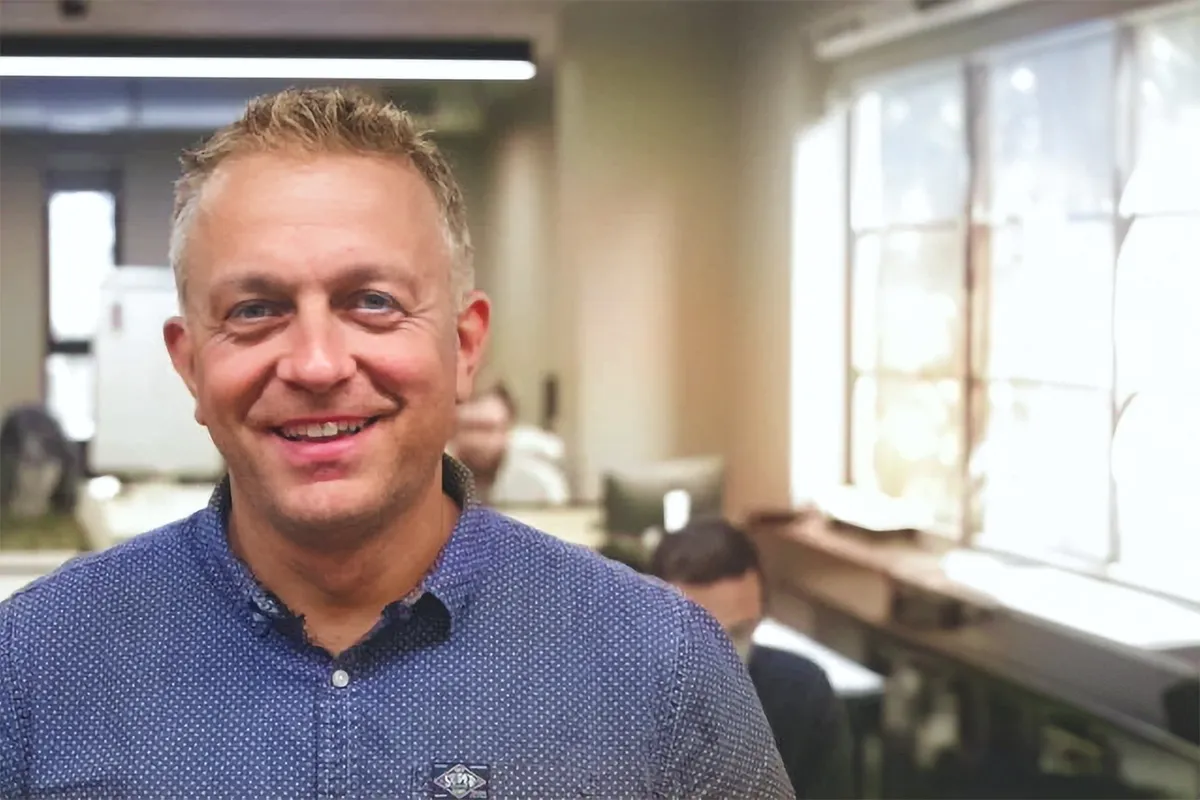 A man in a blue shirt smiling at the camera.