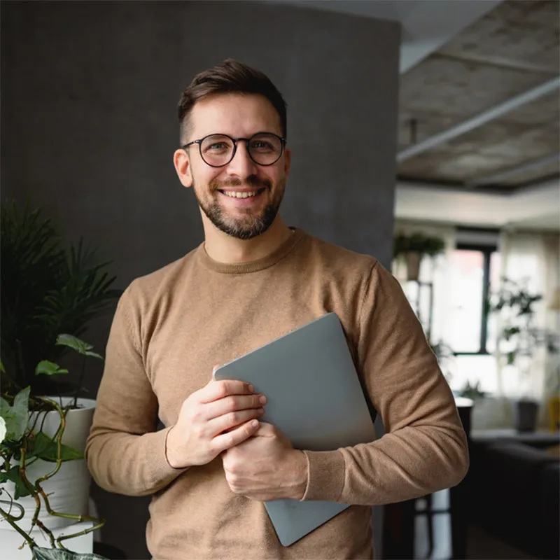 A man with glasses holding a laptop computer.